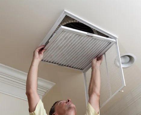 Man replacing the filter in a ceiling air return vent