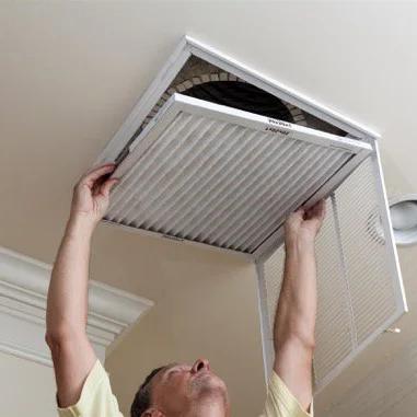 Man replacing the filter in a ceiling air return vent