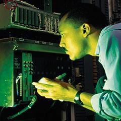 Technician inspecting equipment inside a control cabinet under green light