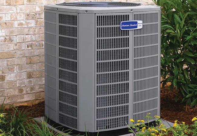 American Standard outdoor air conditioning unit beside a brick wall