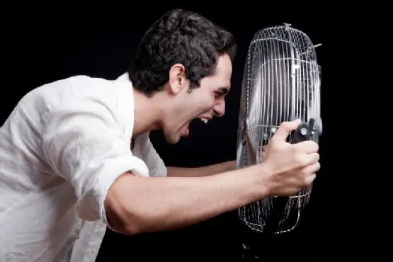 Man shouting into a small fan held up to his face