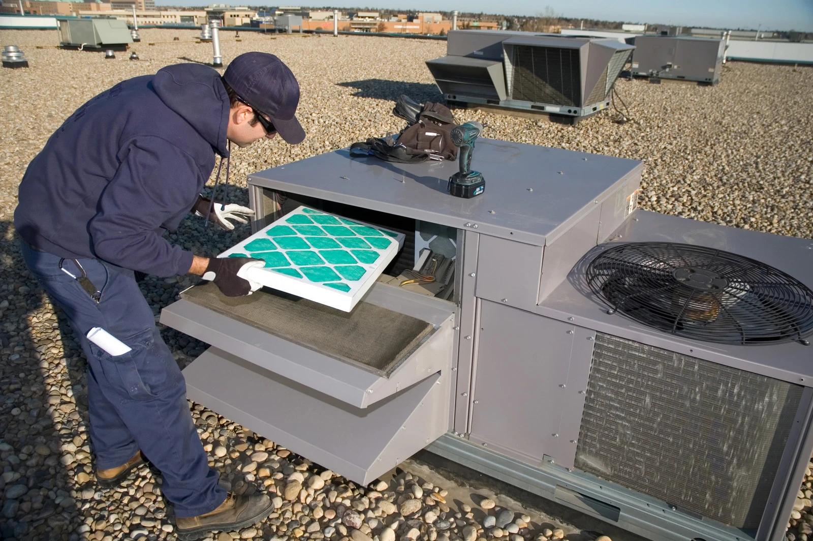 Technician replacing the filter in a rooftop HVAC unit