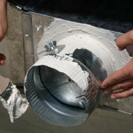 Hands brushing mastic sealant onto a metal duct collar