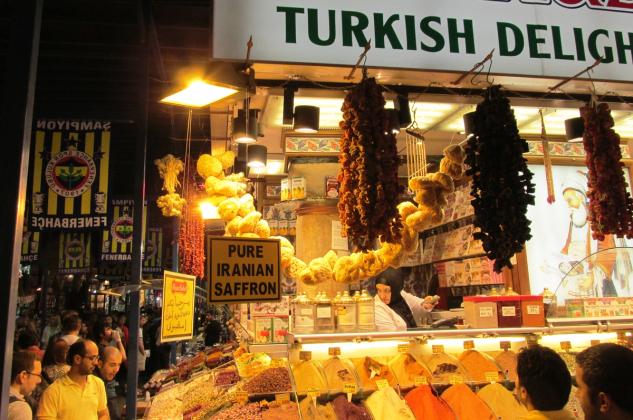 A spice stall inside Istanbul's Spice Bazaar, with labelled bins of spices, hanging natural sponges and dried fruit, and a 'Turkish Delight' sign.