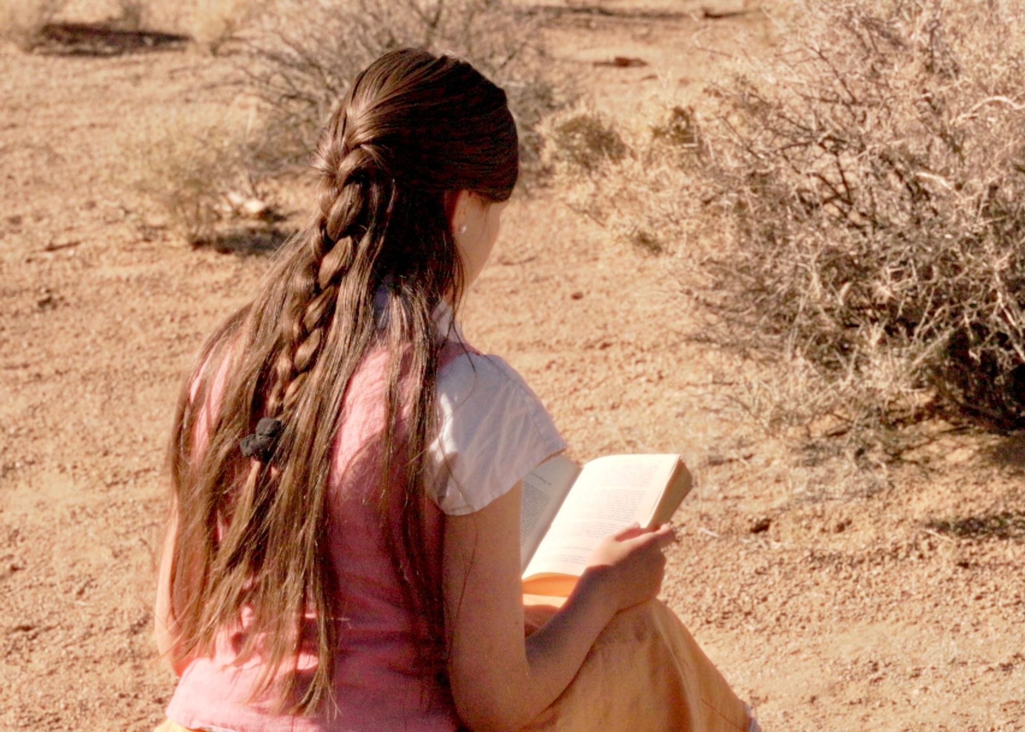 Young woman with braided hair reading in natural outdoor setting - Traditional self care journal by The Royal Family musical family