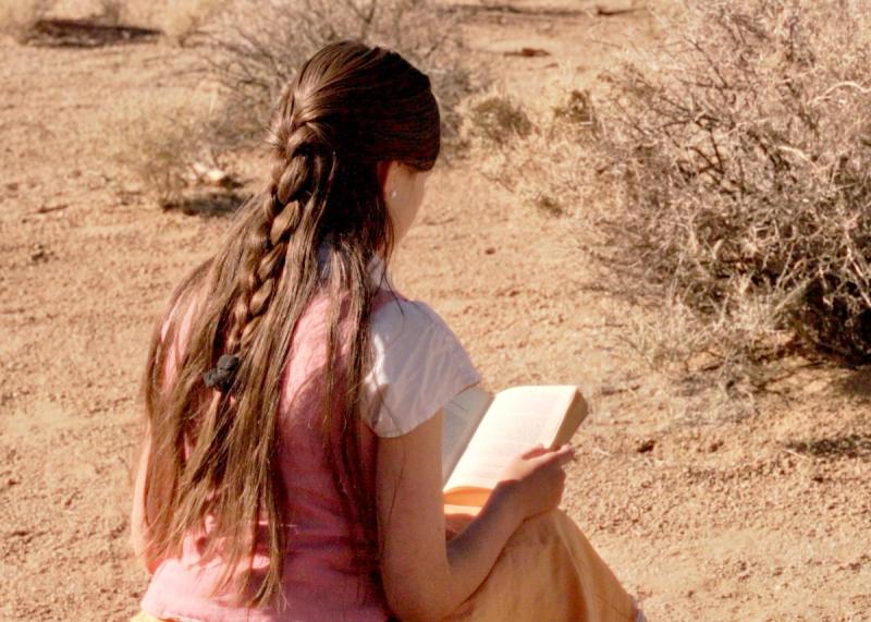 Young woman with braided hair reading in natural outdoor setting - Traditional self care journal by The Royal Family musical family