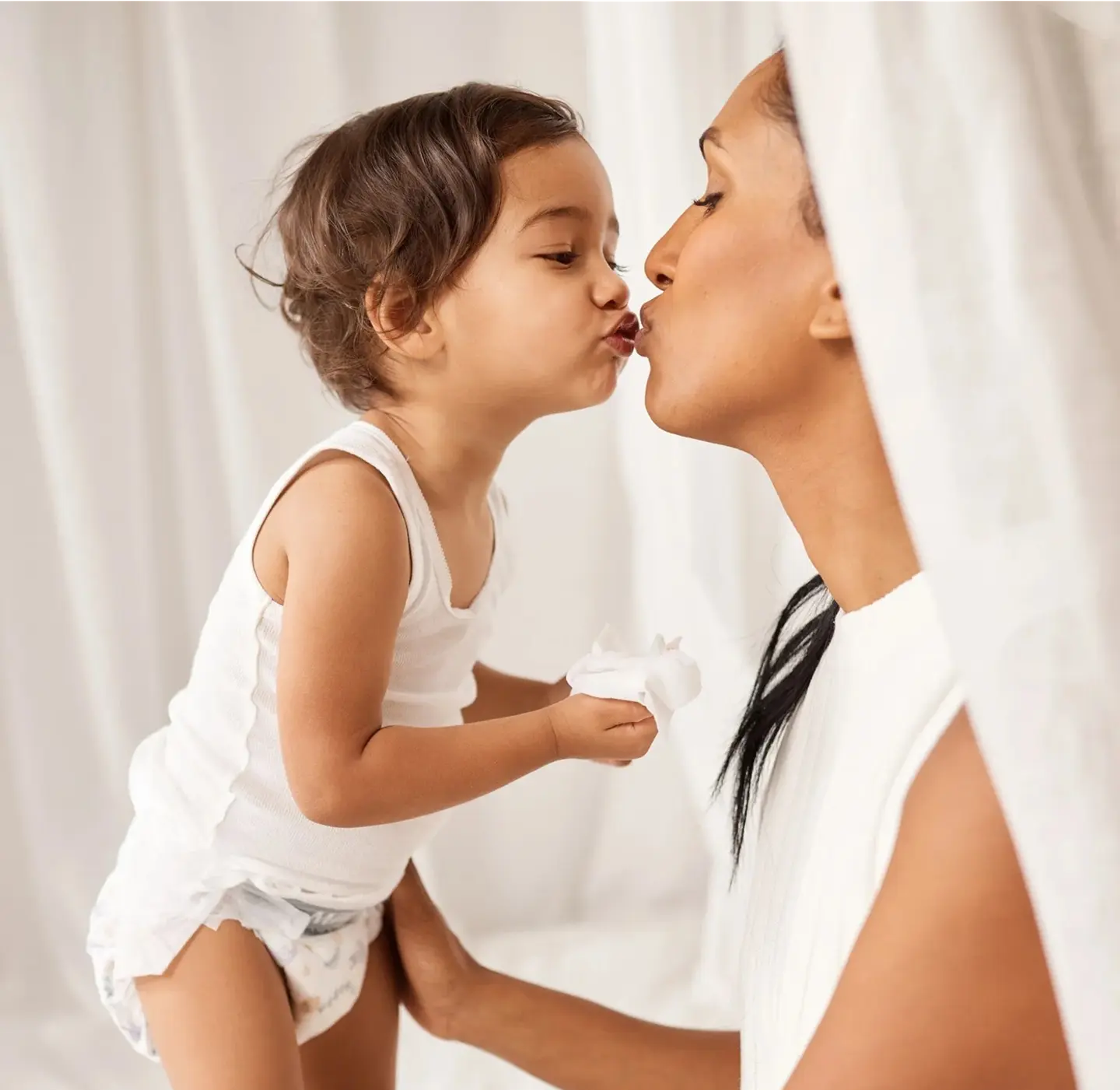 Parent lifting a toddler wearing a Millie Moon diaper for a kiss