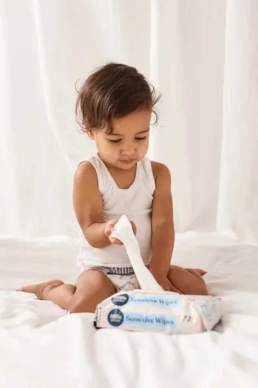Toddler in a Millie Moon diaper pulling a wipe from a pack of Millie Moon Sensitive Wipes