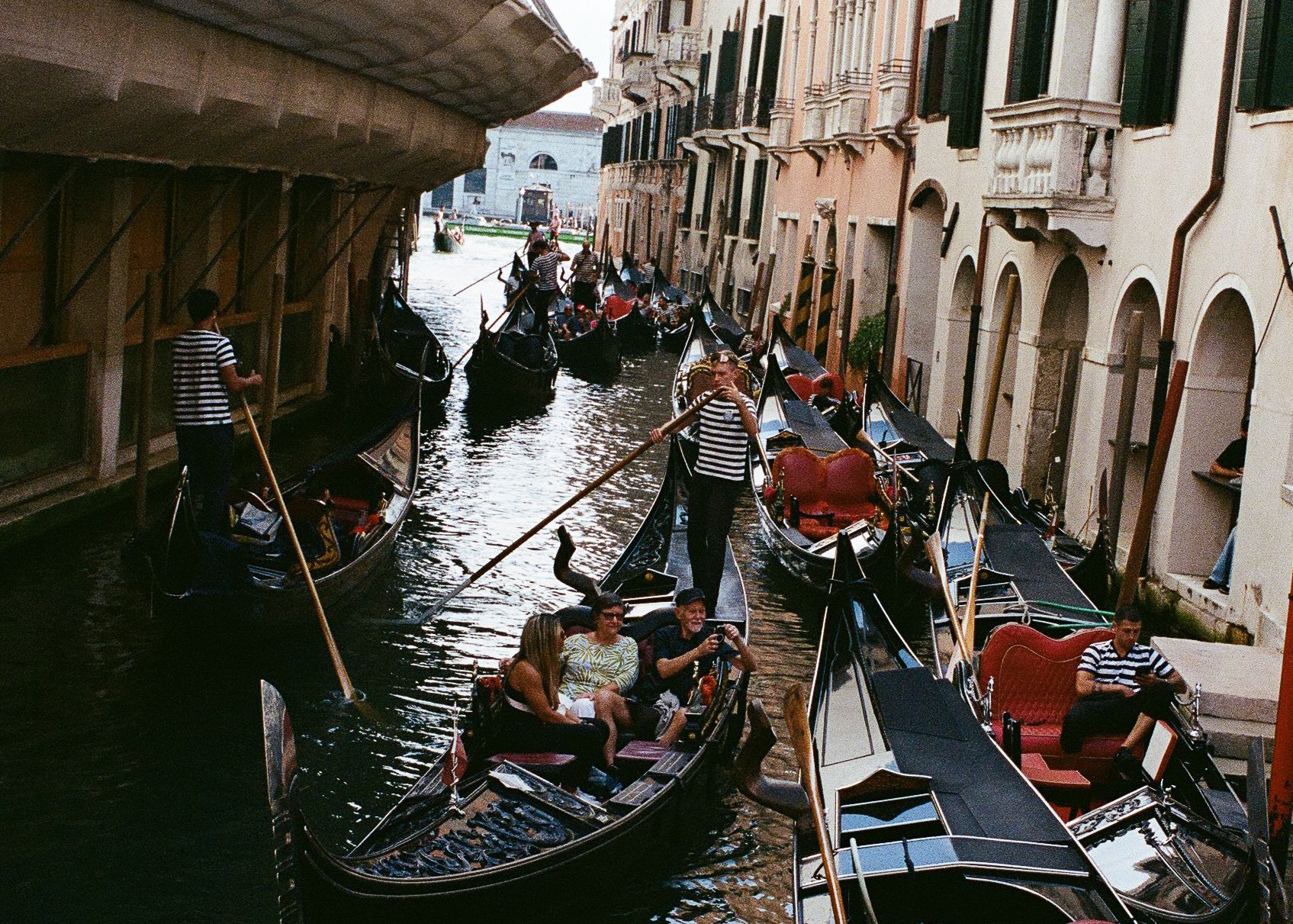 Gondolas competing for space in a narrow canal, where centuries-old traditions meet modern tourism.