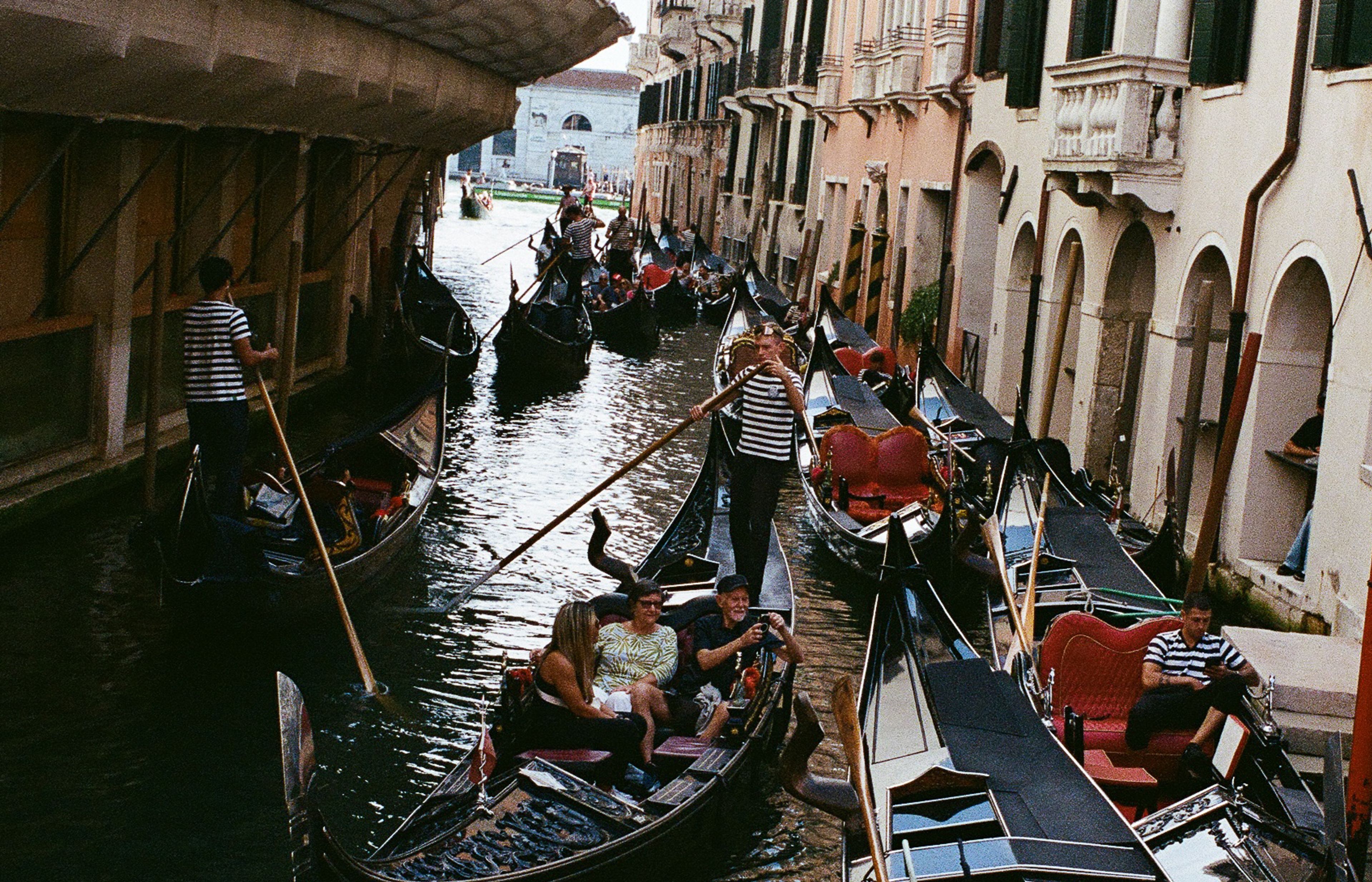 Gondolas competing for space in a narrow canal, where centuries-old traditions meet modern tourism.