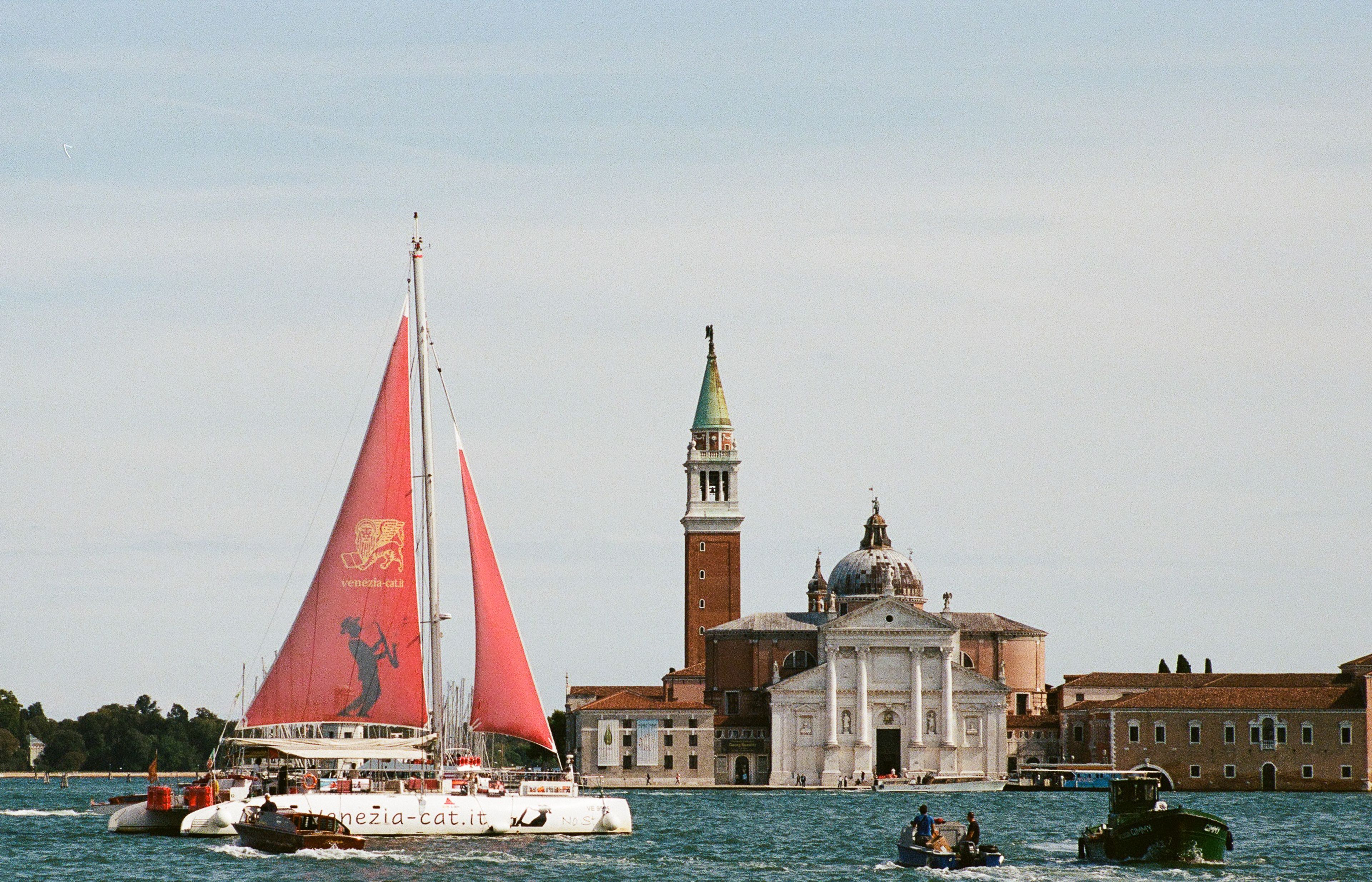 A red sail crossing the lagoon in front of San Giorgio Maggiore.