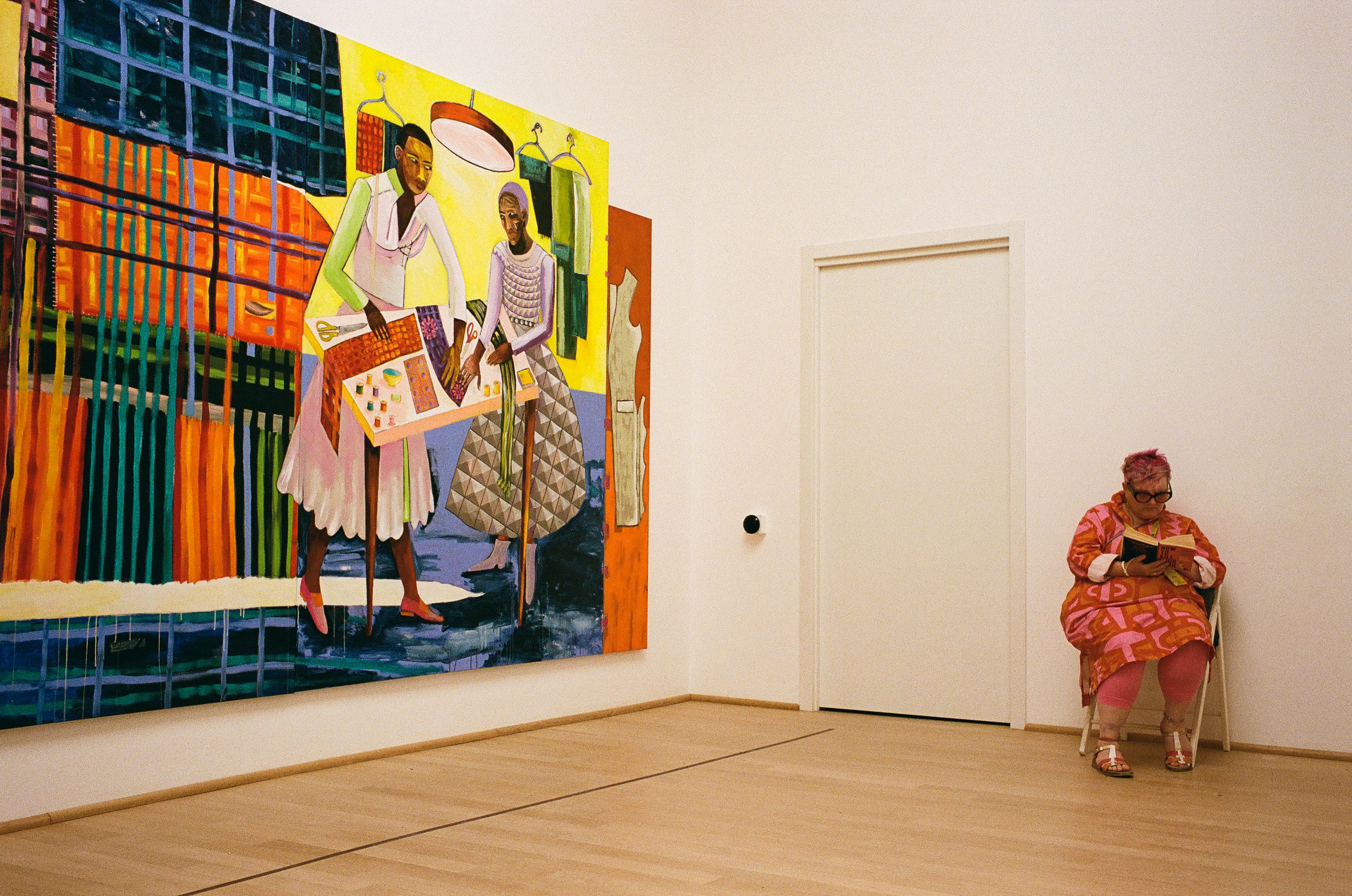 A seated visitor whose colours echo the nearby painting.