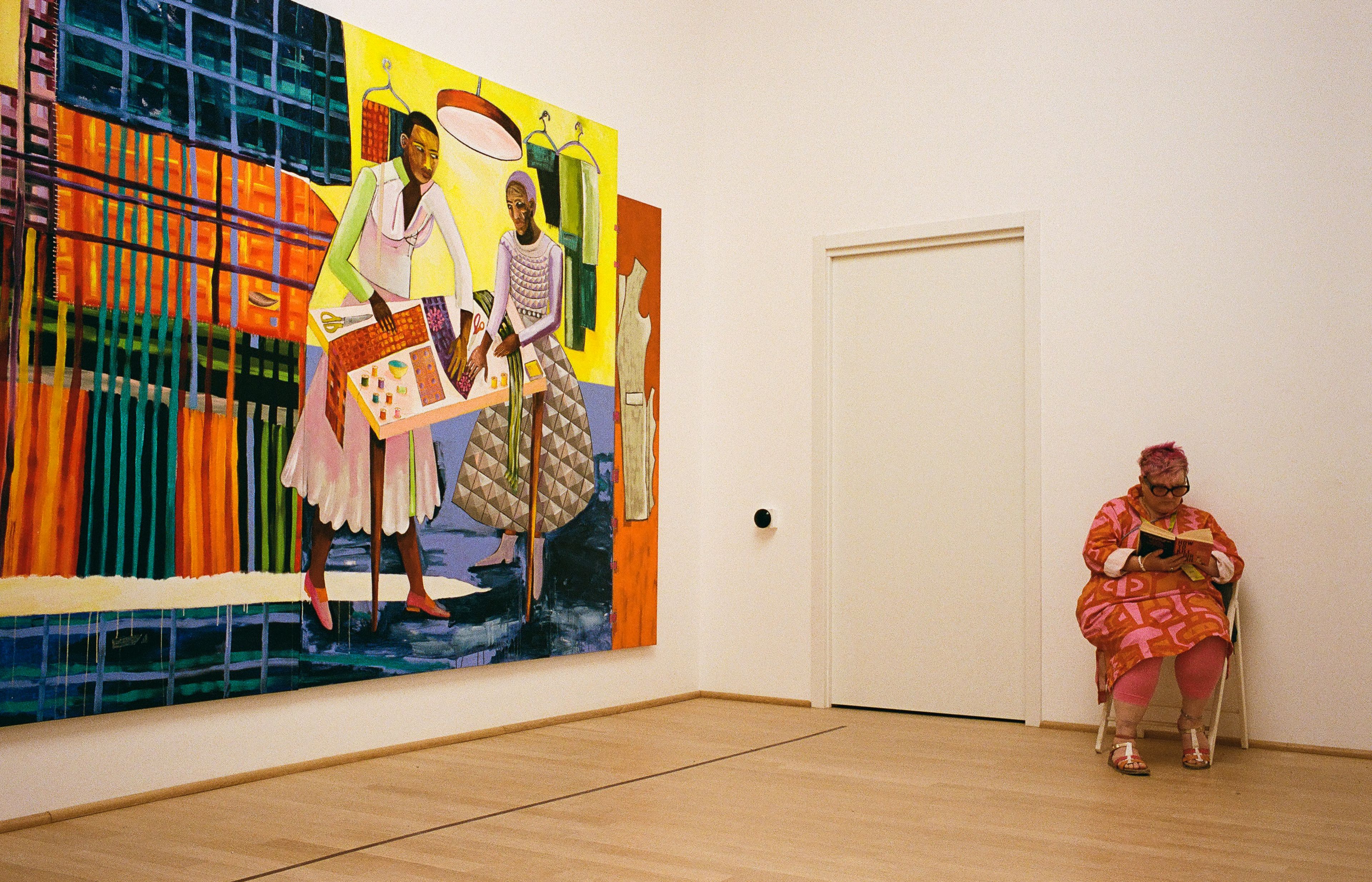 A seated visitor whose colours echo the nearby painting.