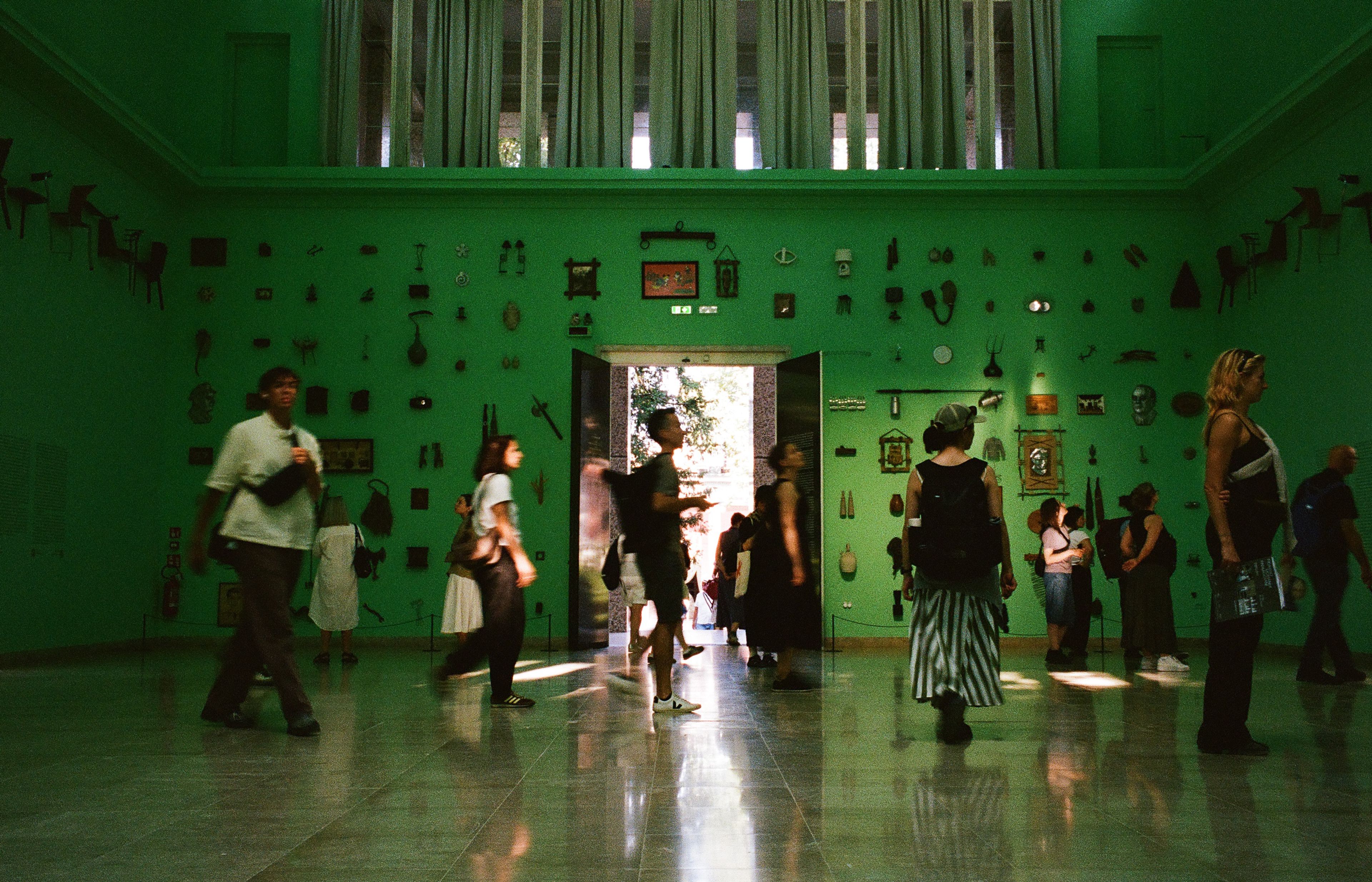 Observing the observers — visitors moving through the green-lit German Pavilion.