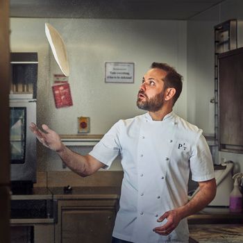 Chef throwing pizza at his restaurant