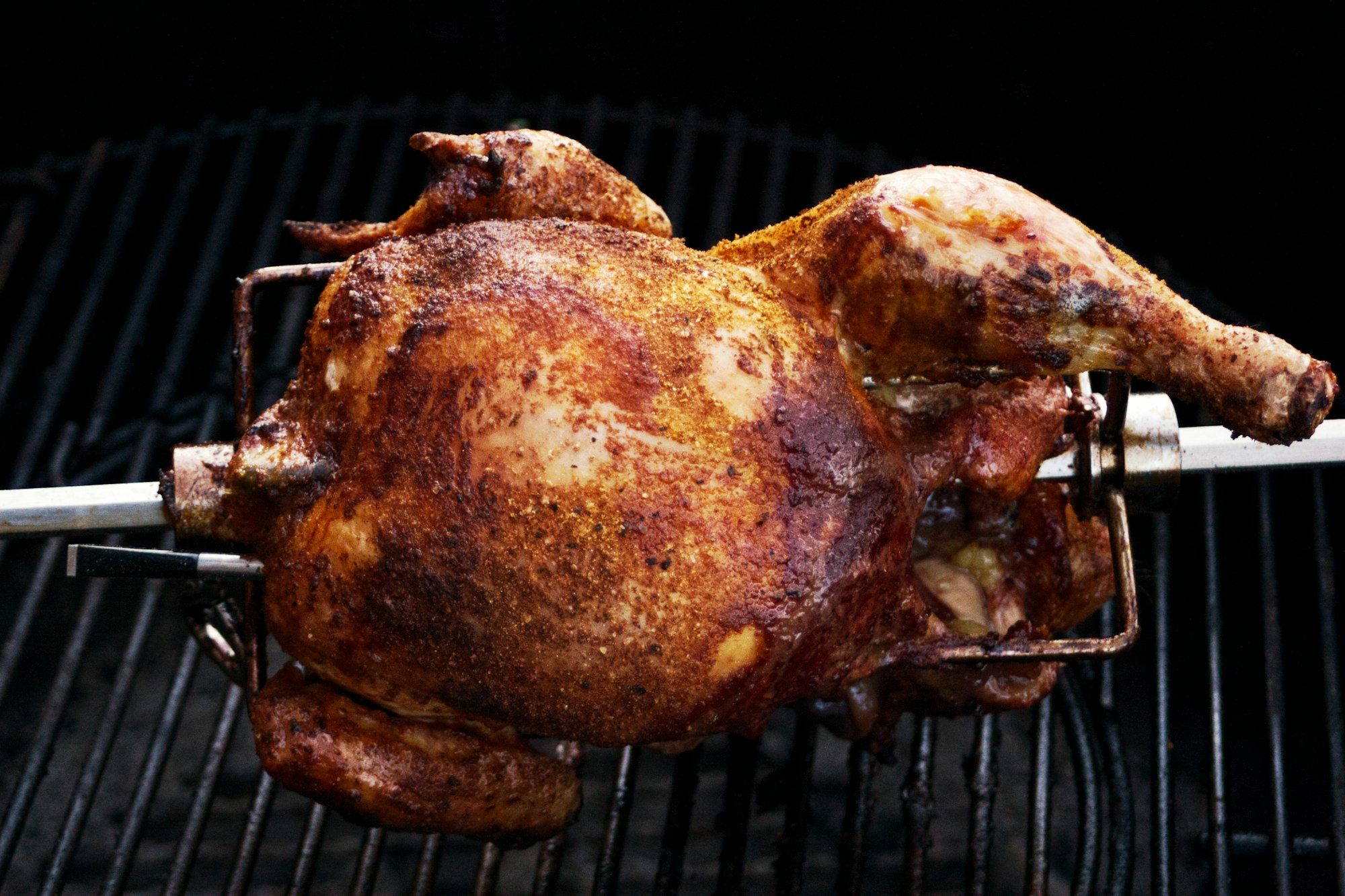 Pollo dorato che gira sullo spiedo sopra la brace