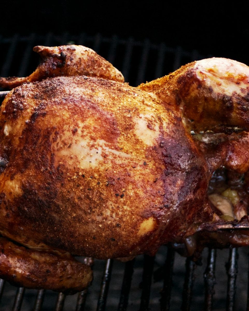 Pollo dorato che gira sullo spiedo sopra la brace