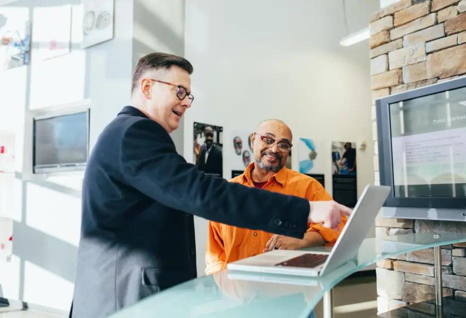 Two business professionals collaborating on a laptop to explore Zlendo Realty AI software sales and consulting opportunities