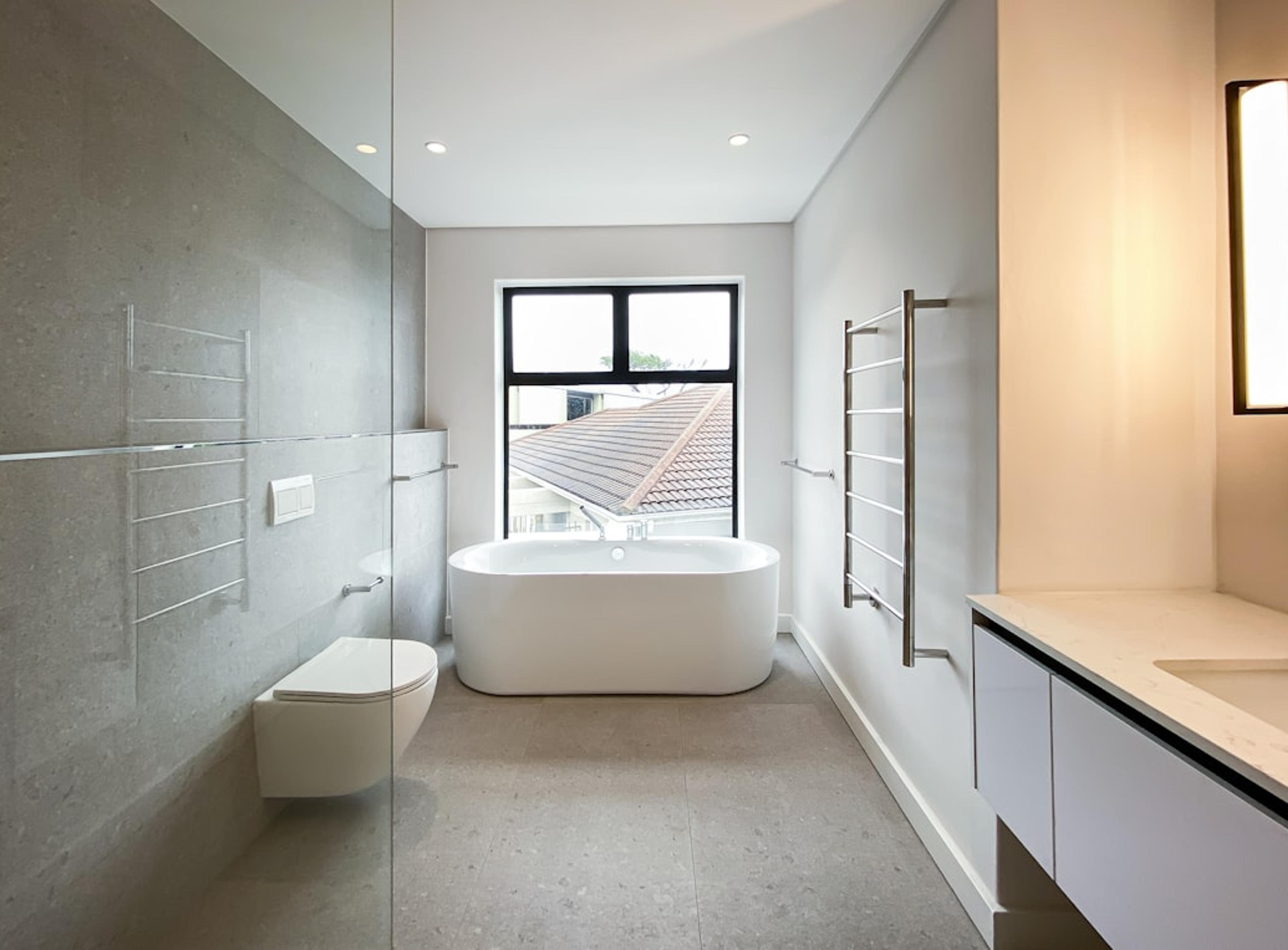 Minimalist gray bathroom with freestanding tub and glass shower