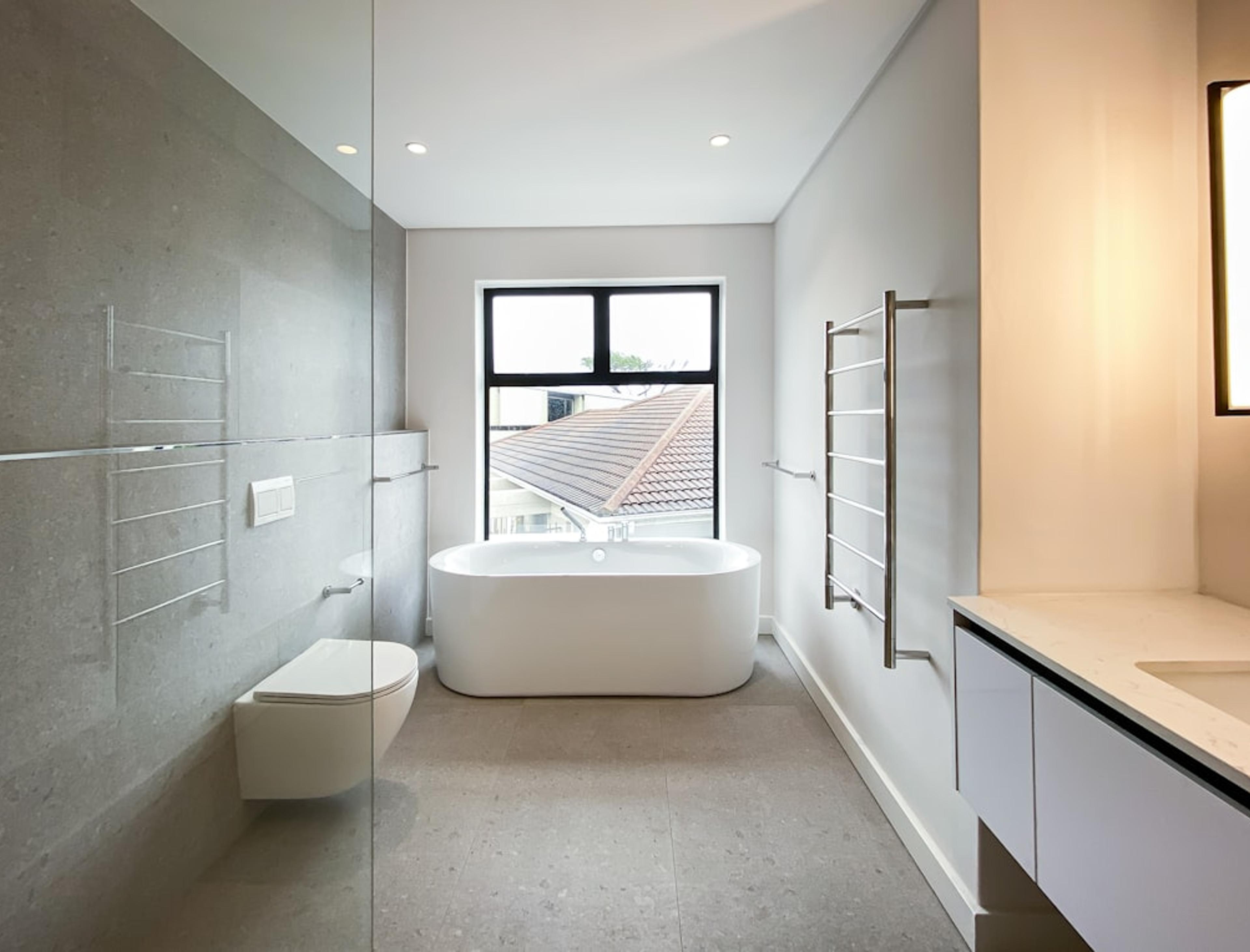 Minimalist gray bathroom with freestanding tub and glass shower