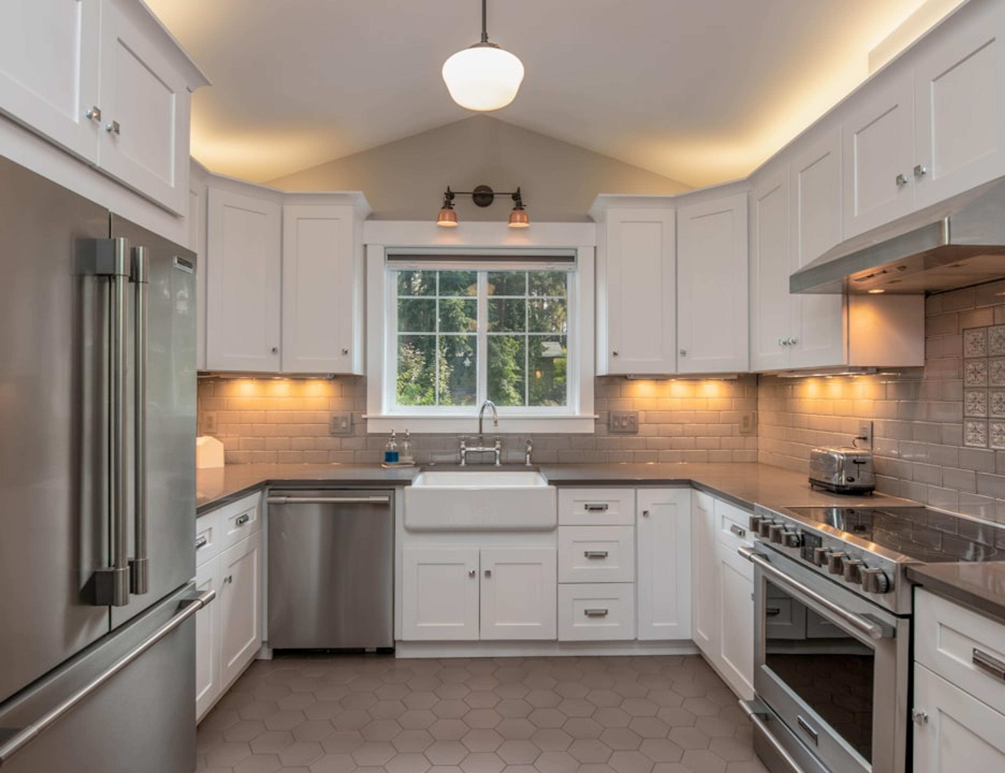 Classic white kitchen with farmhouse sink, stainless appliances, and arched ceiling