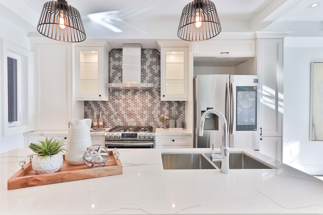 White kitchen with marble-pattern backsplash, cage pendants, and quartz island