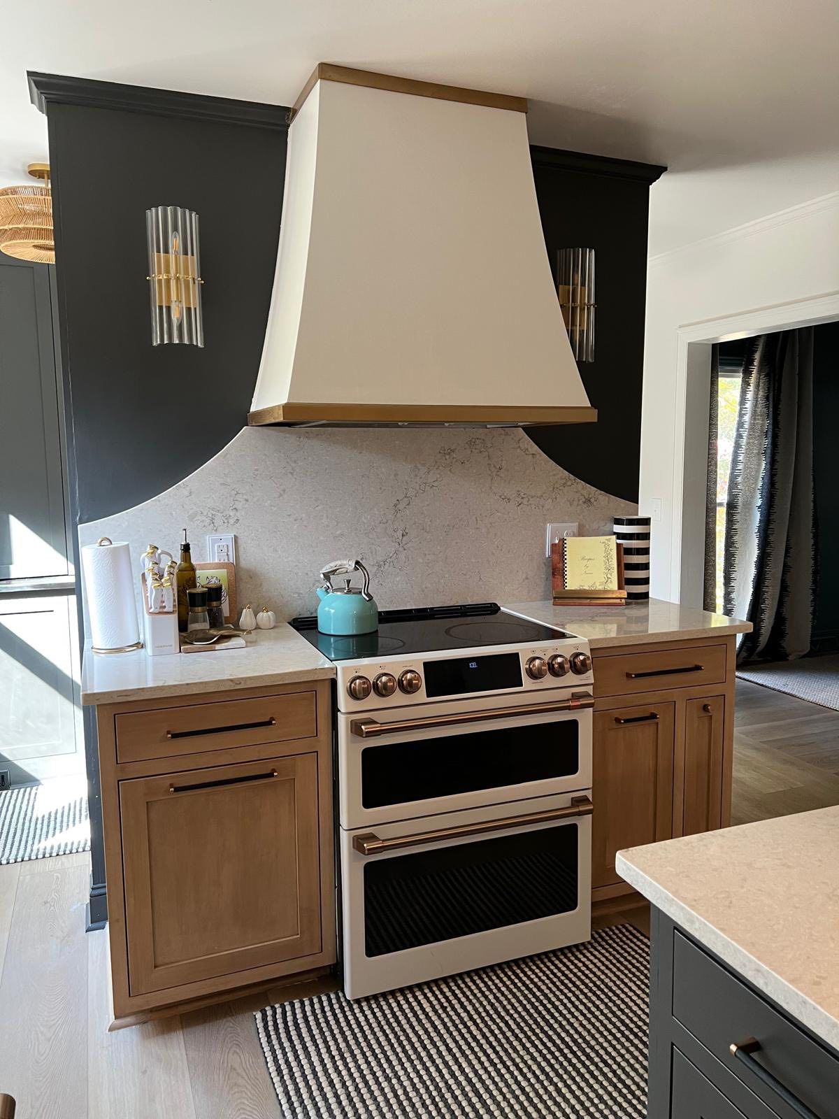 Custom cream range hood with dark green island and professional range