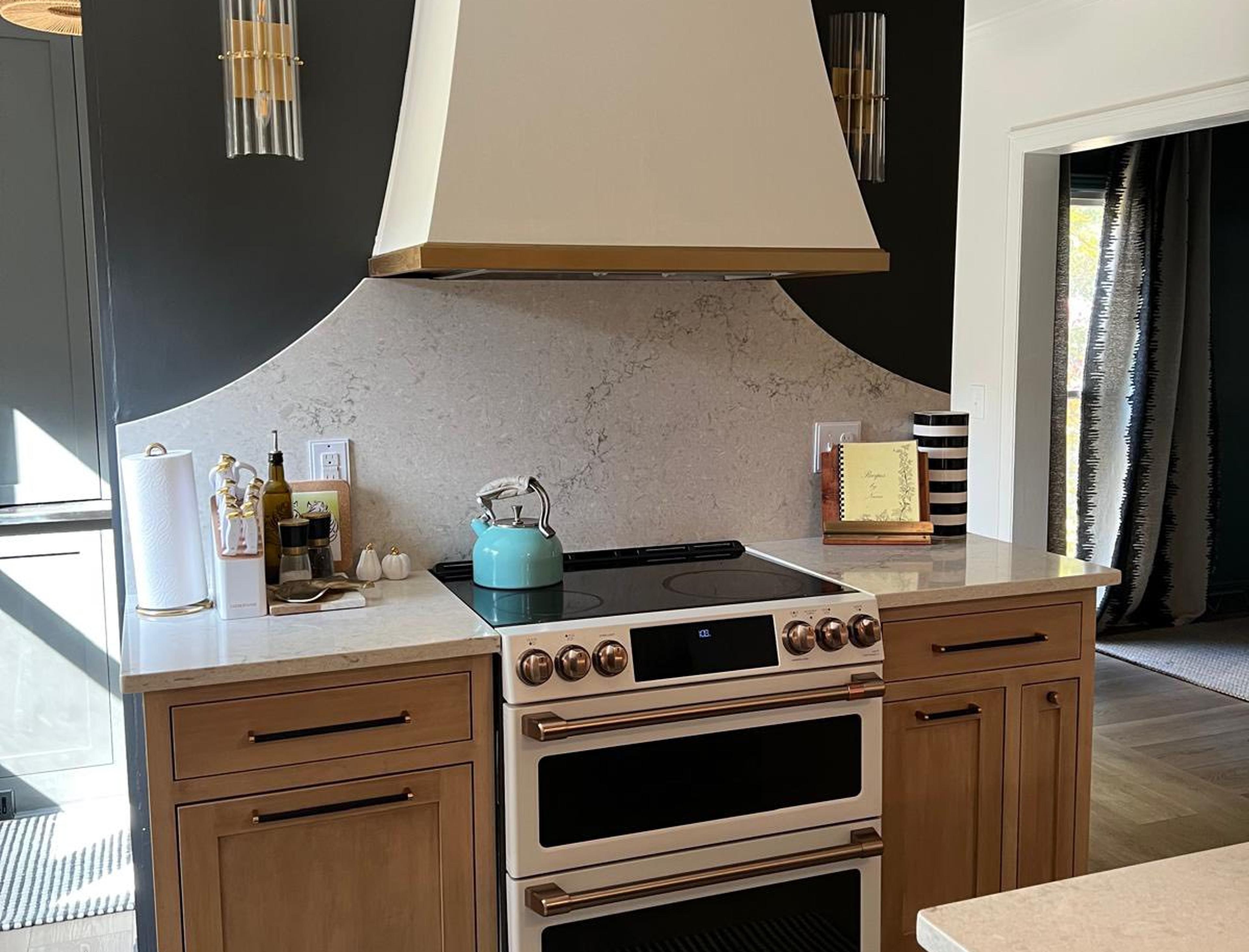 Custom cream range hood with dark green island and professional range