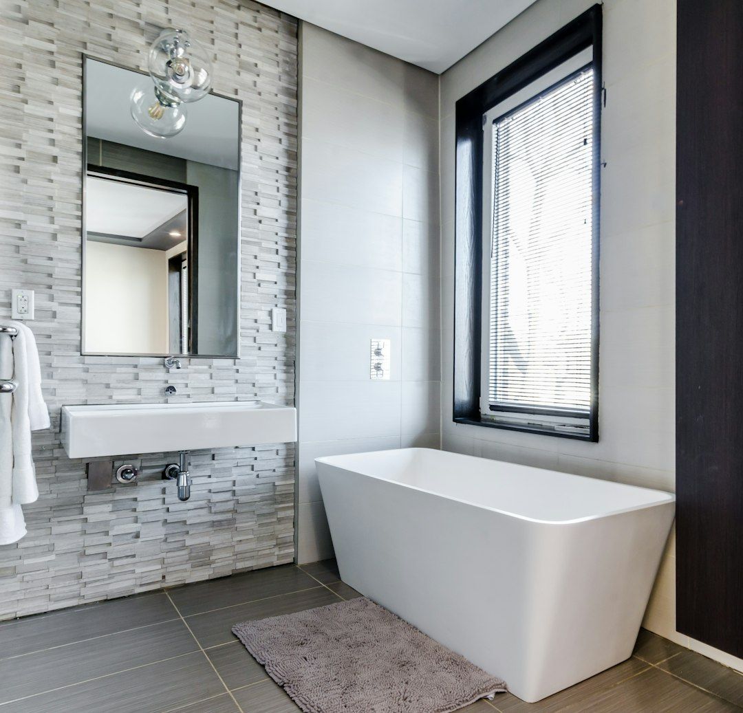 Freestanding tub against a stone tile accent wall