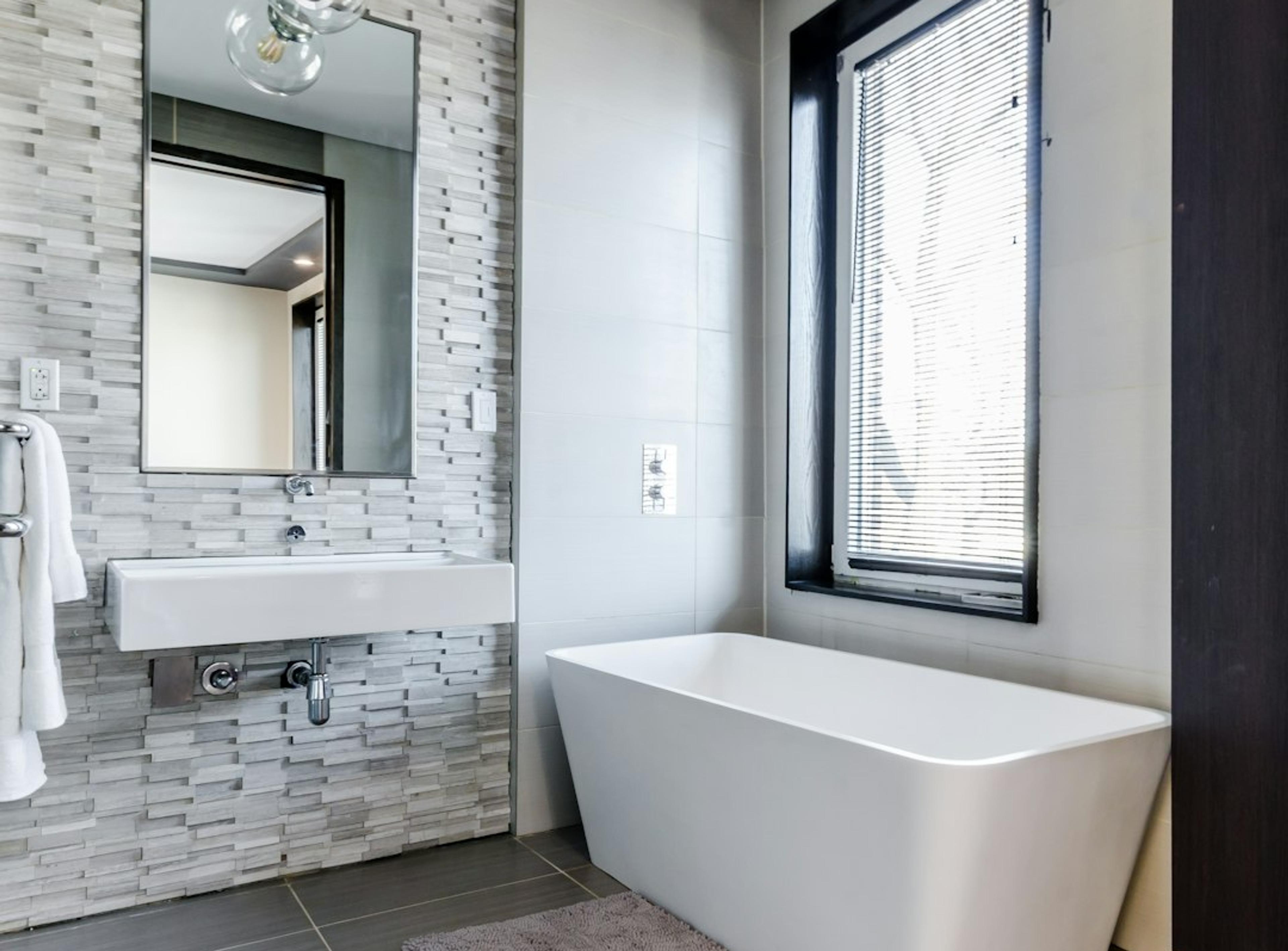 Freestanding tub against a stone accent wall