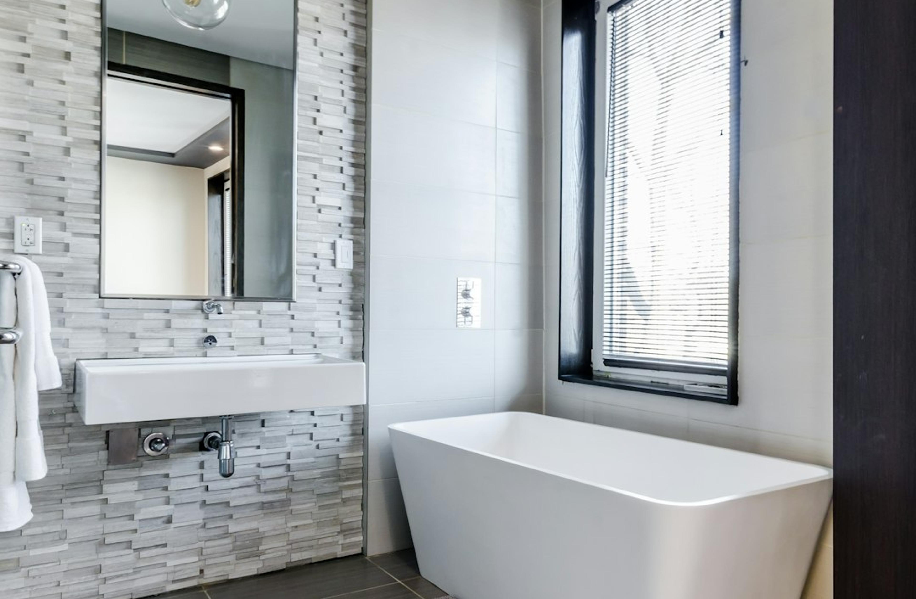Freestanding tub against a stone tile accent wall