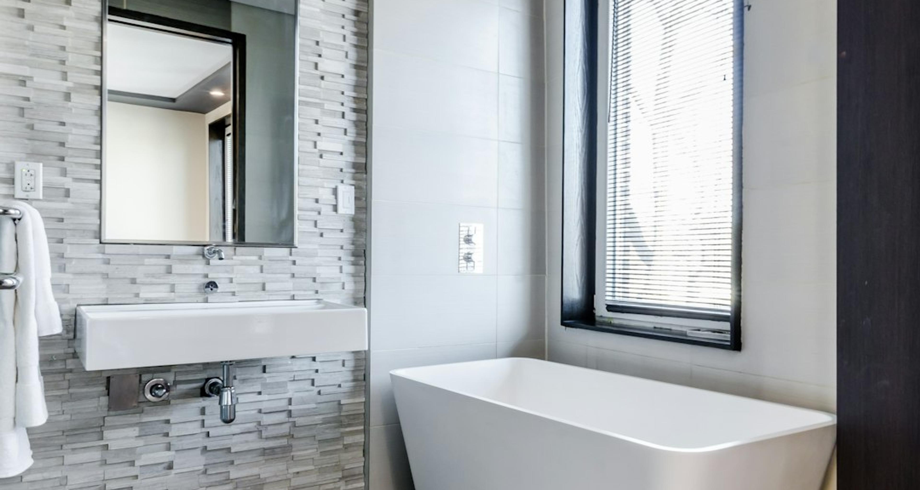 Freestanding tub against a stone tile accent wall