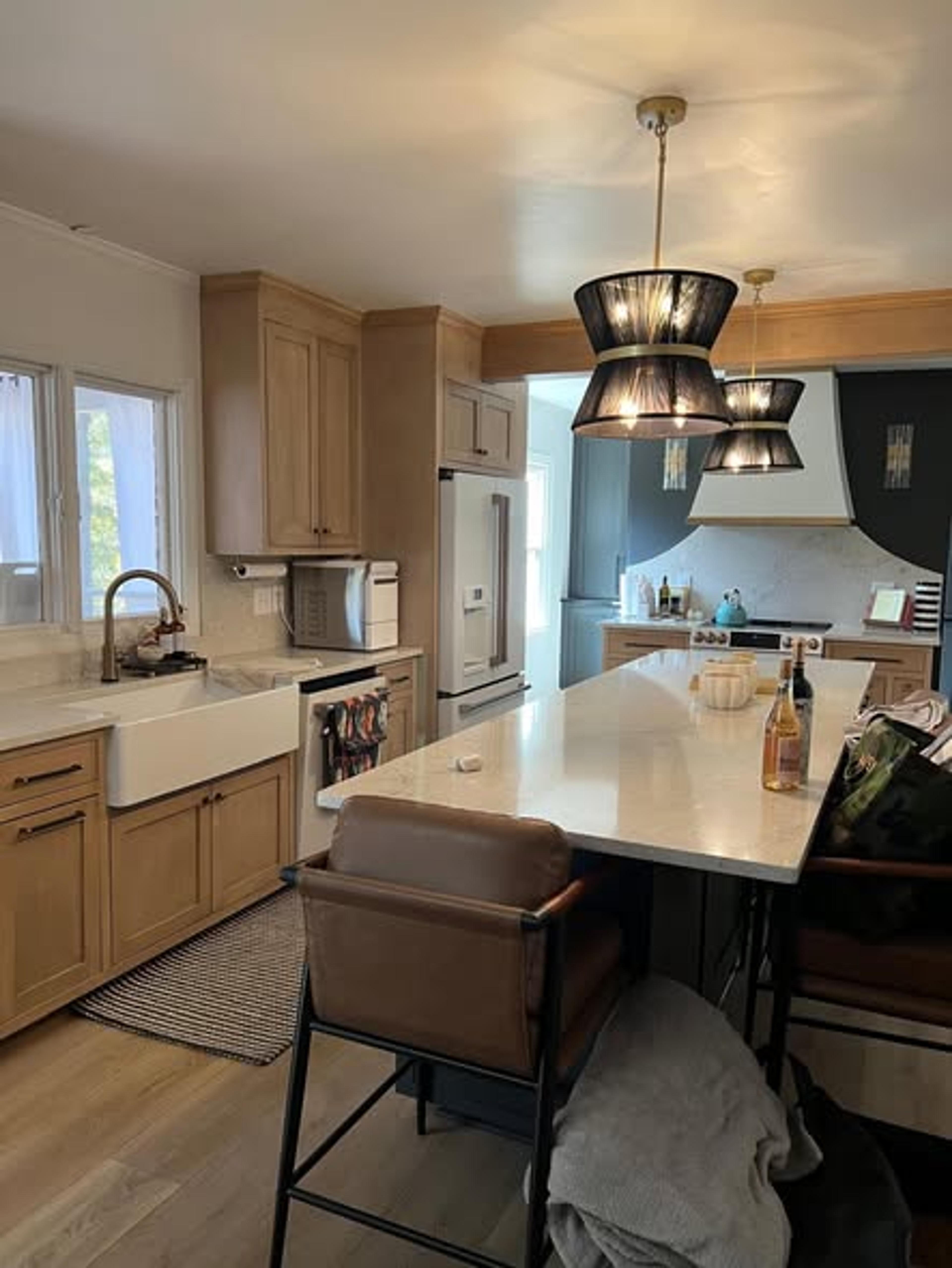 Light wood kitchen with farmhouse sink, island seating, and lantern pendant