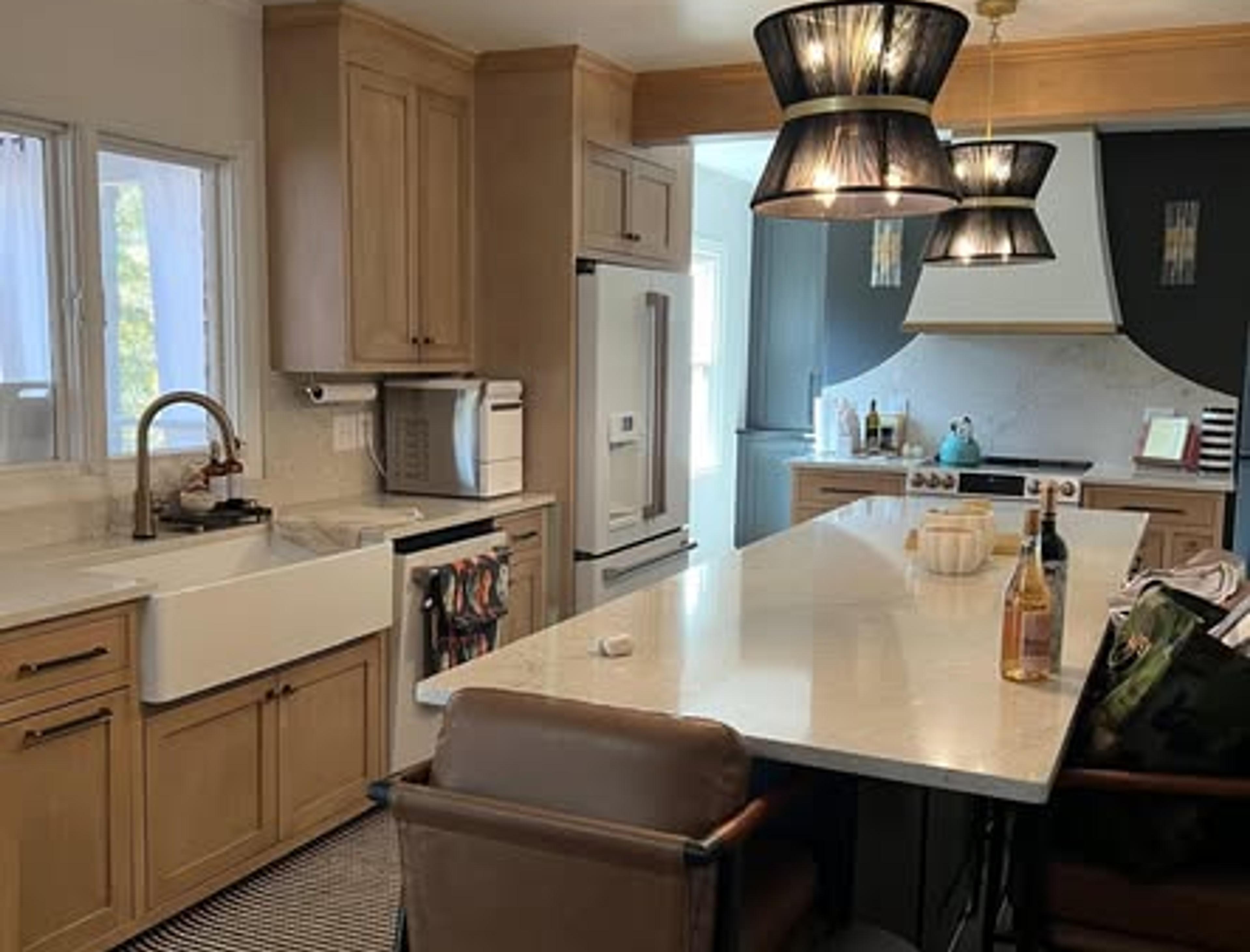 Natural wood shaker cabinets with farmhouse sink and white quartz counters