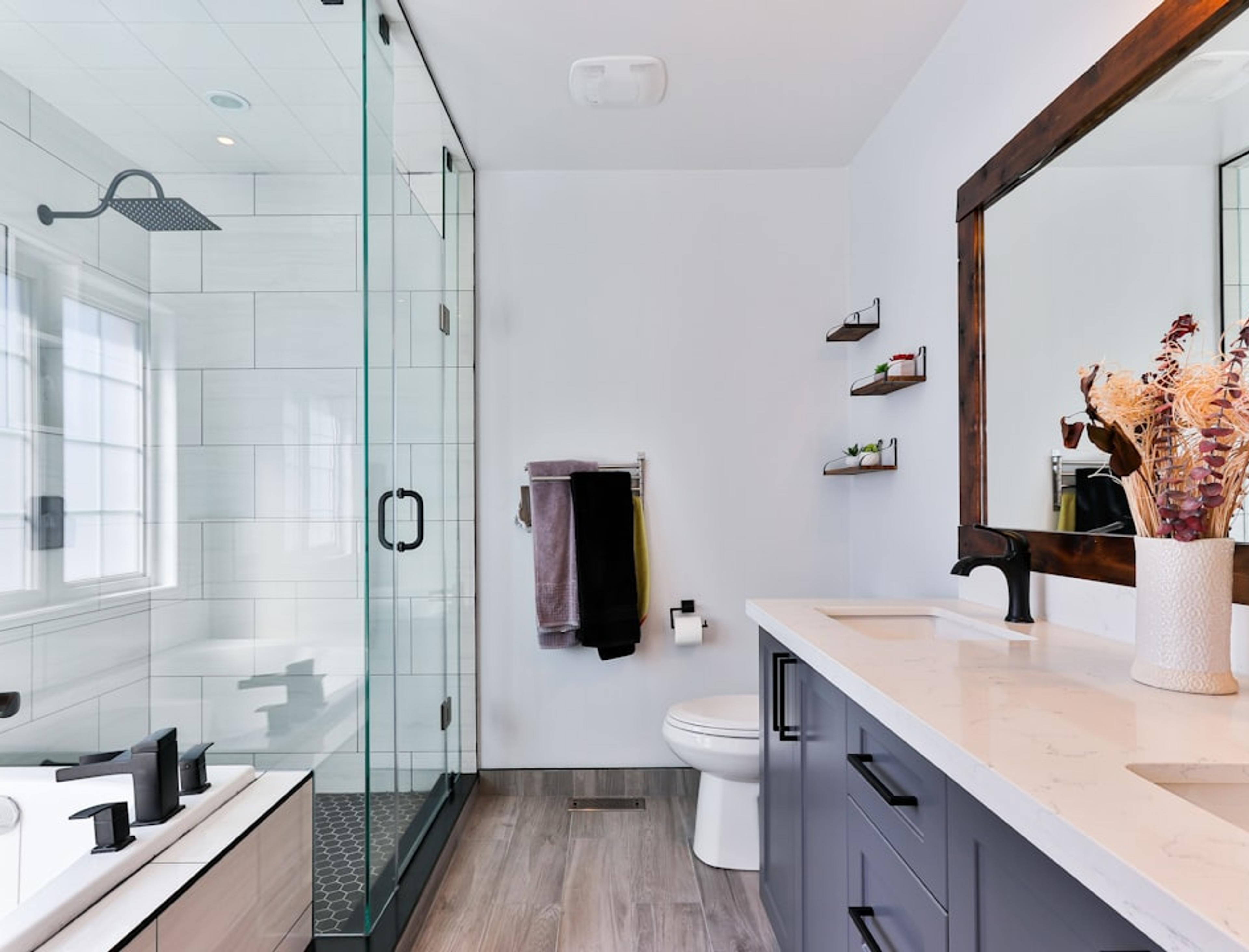 Glass shower and dark vanity with wood-look floors