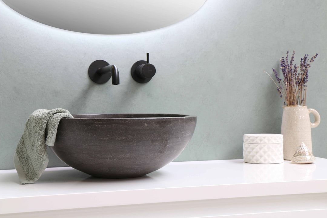 Stone vessel basin with black wall faucet