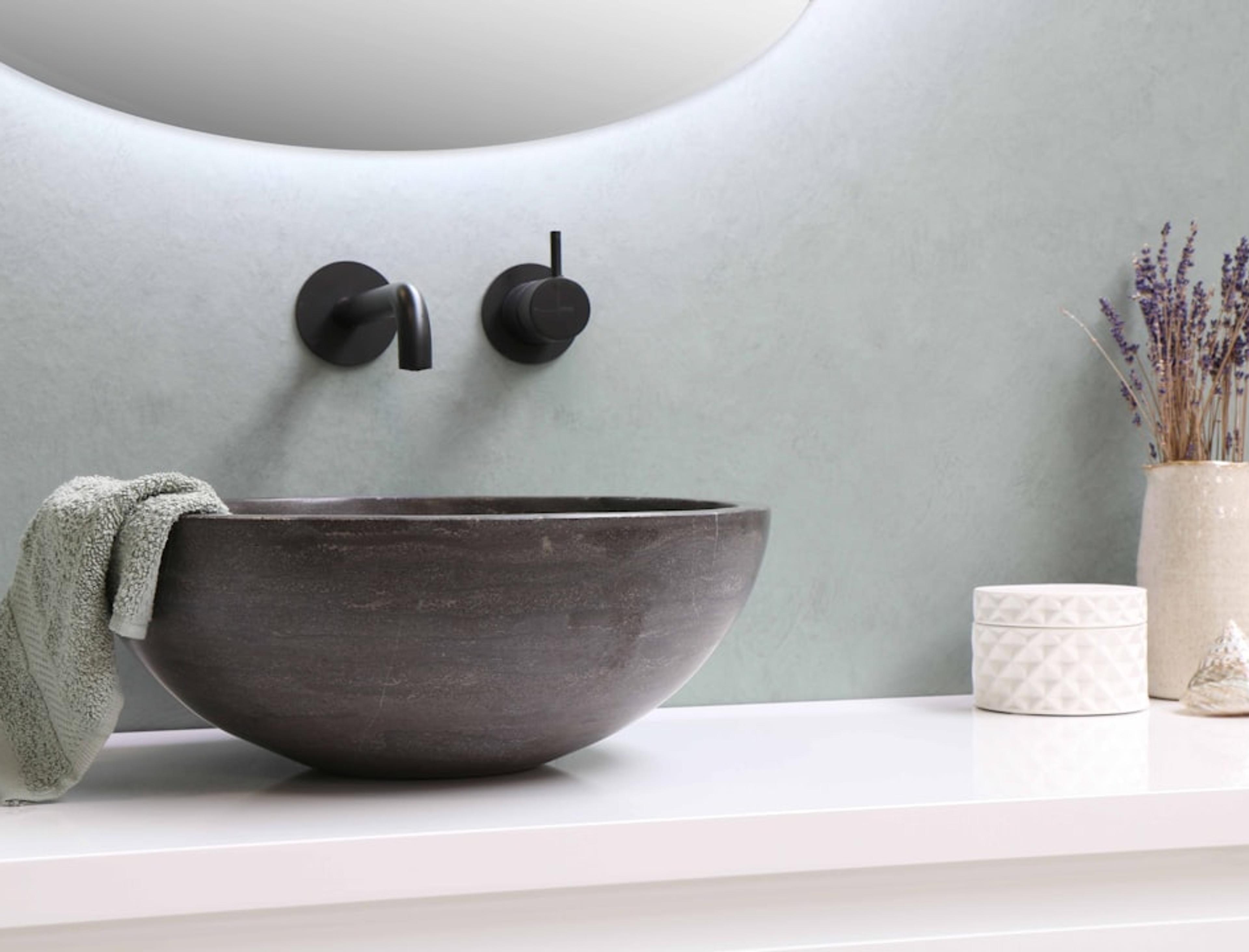 Round stone vessel basin with black wall-mounted faucet