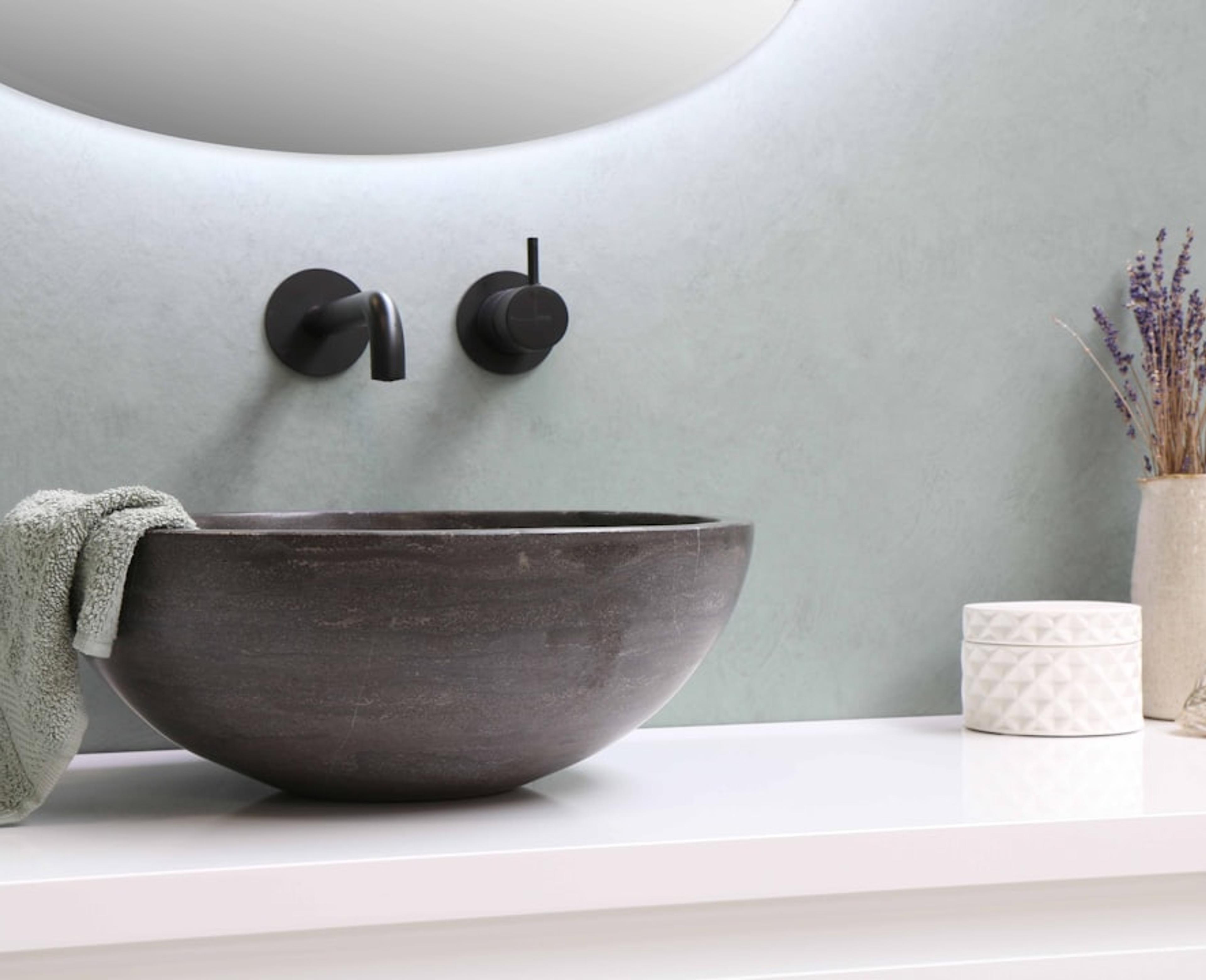 Stone vessel basin with black wall faucet