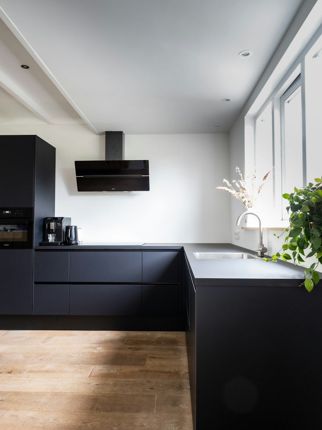 Matte black modern kitchen with warm wood flooring