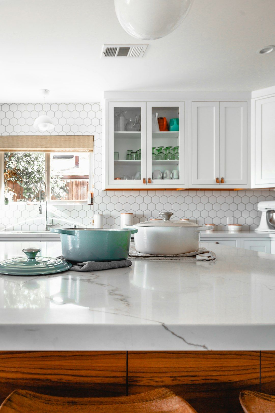 Bright white kitchen with glass-front cabinets and marble countertop