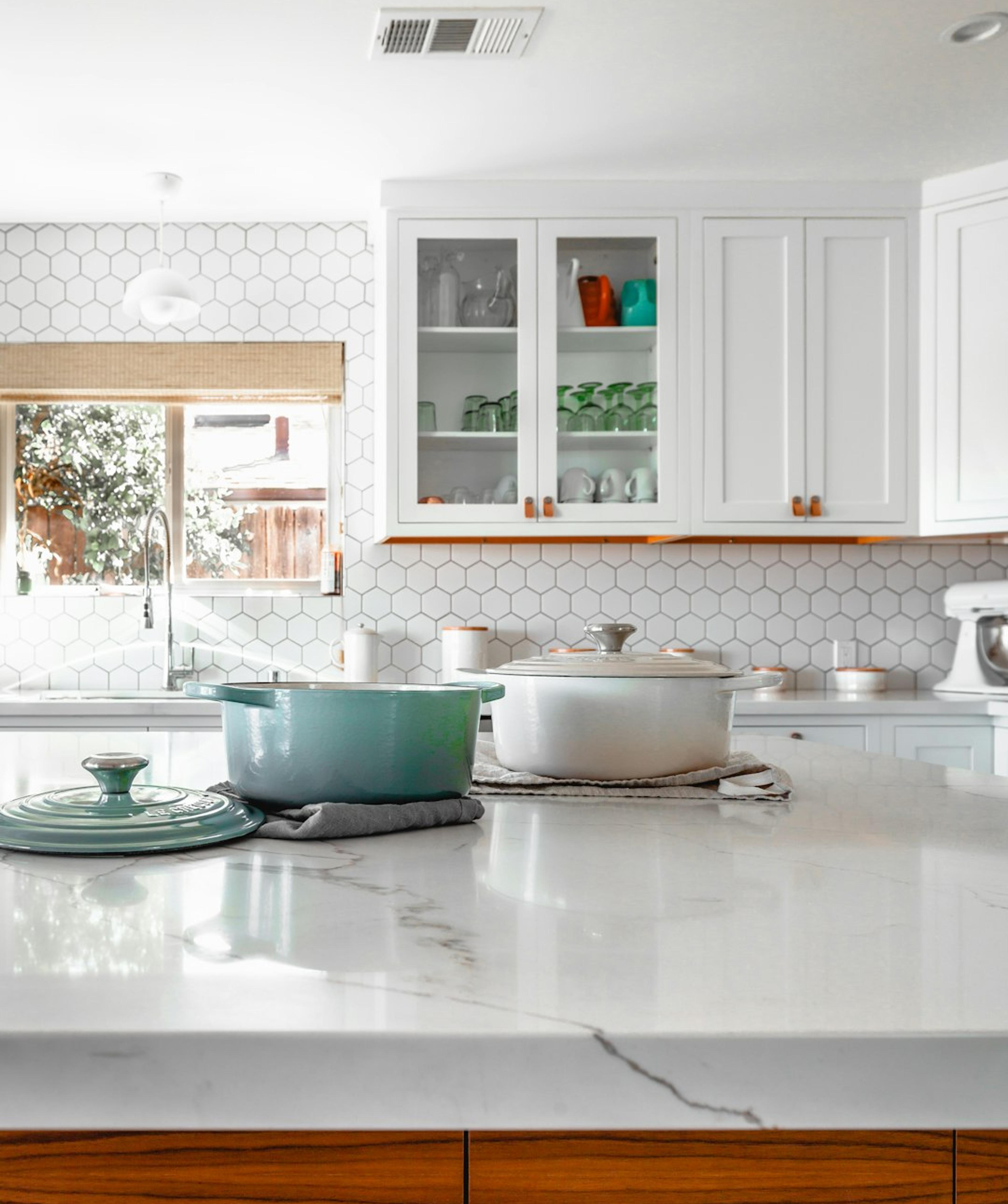 Bright white kitchen with glass-front cabinets and marble countertop