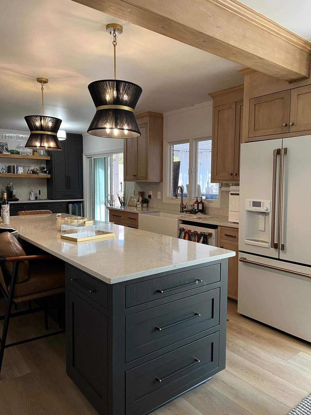 Cream perimeter cabinets with dark green island, farmhouse sink, and black pendants