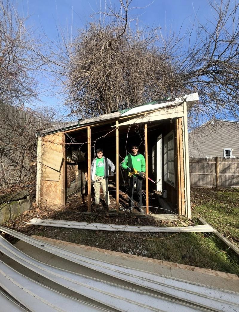Crew members inside an old shed being torn down by hand