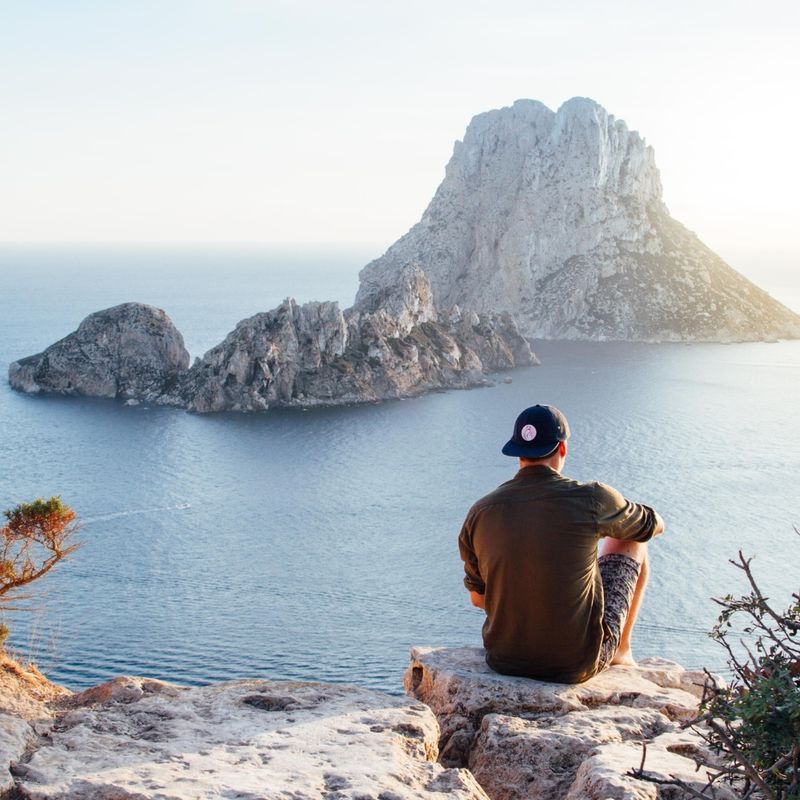 Rear View of Man Sitting on Rock by Sea, Es Vedra island