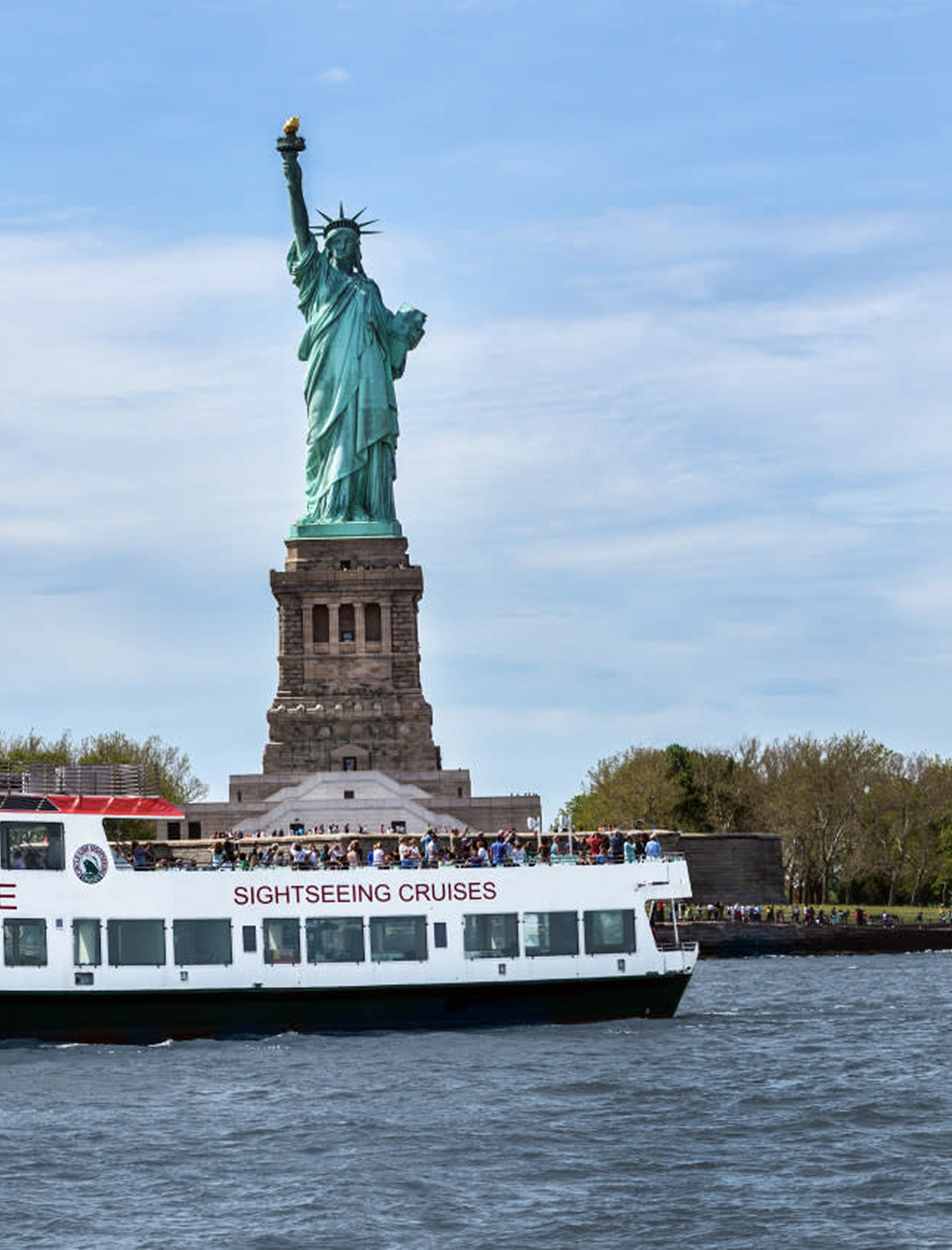 a cruise boat passing the Statue of Liberty