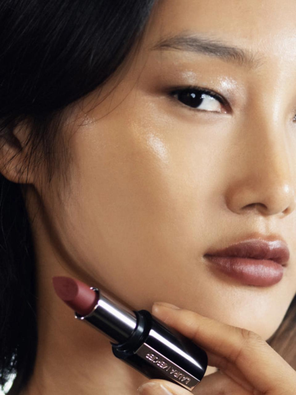 models with glowing skin and holding lipstick