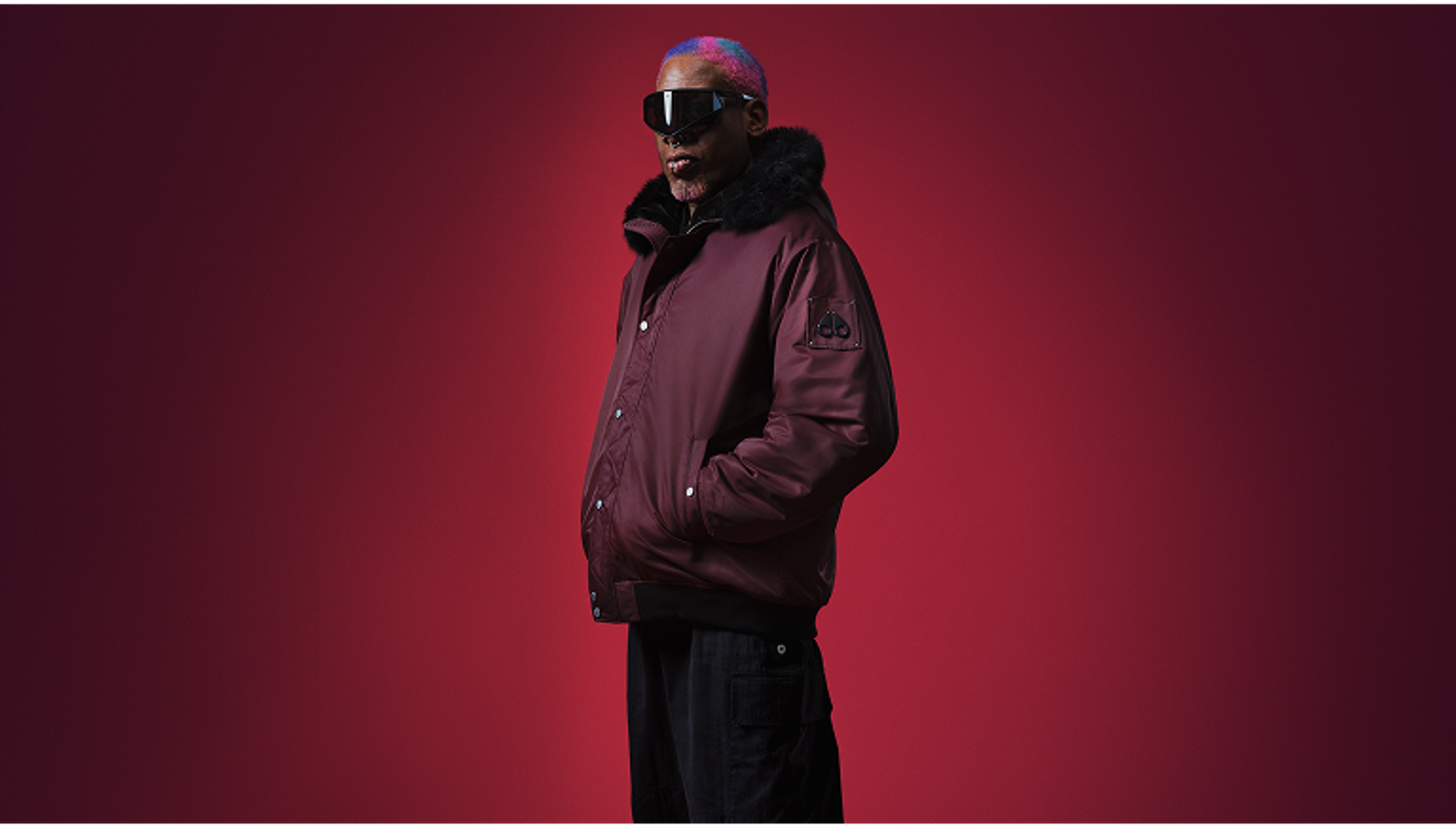 Model wearing dark red jacket and glasses Moose Knuckles