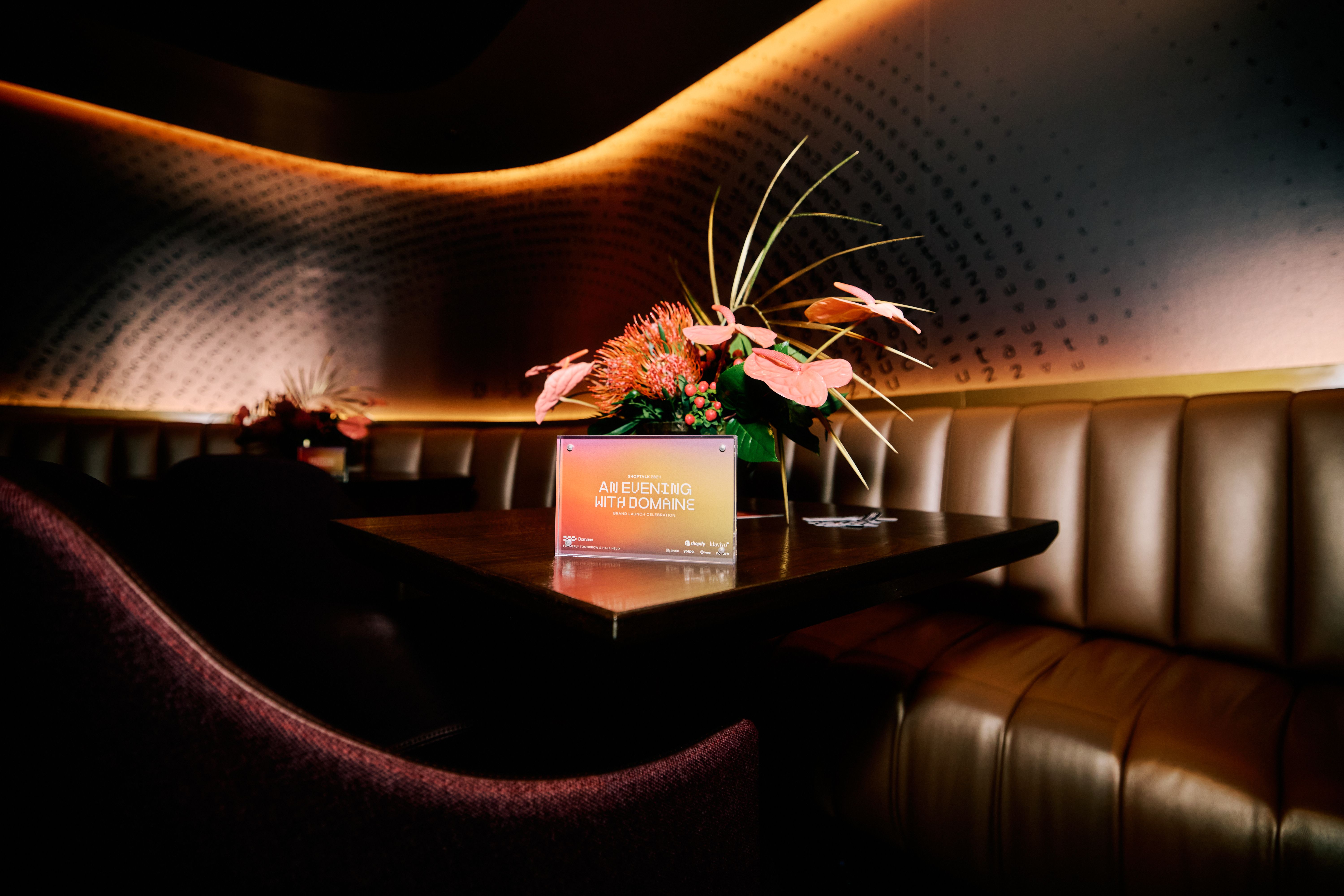 A sign with the words 'An Evening with Domaine' on a table with orange florals