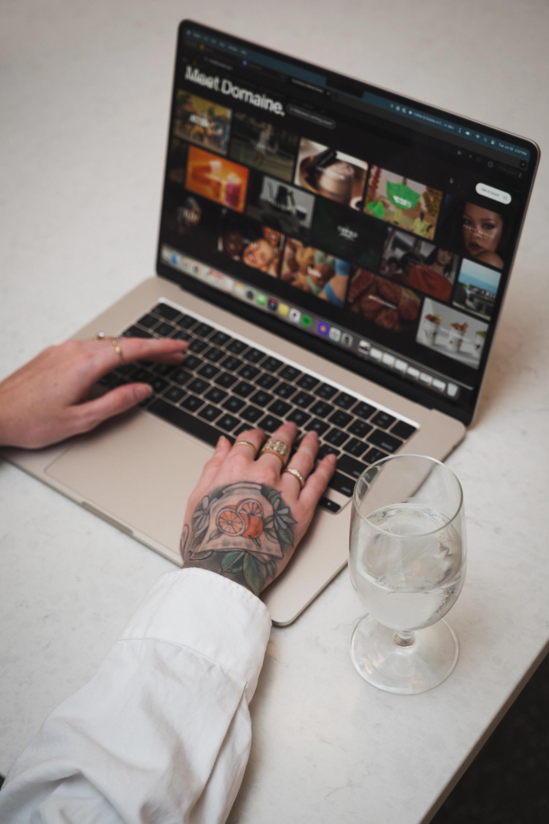 Tattooed hands working on a laptop
