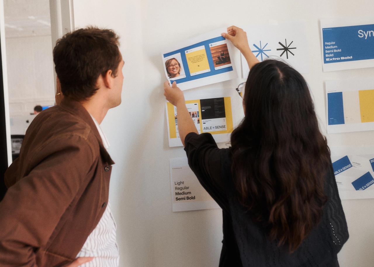 Sarah and Milo pinning brand guidelines to wall